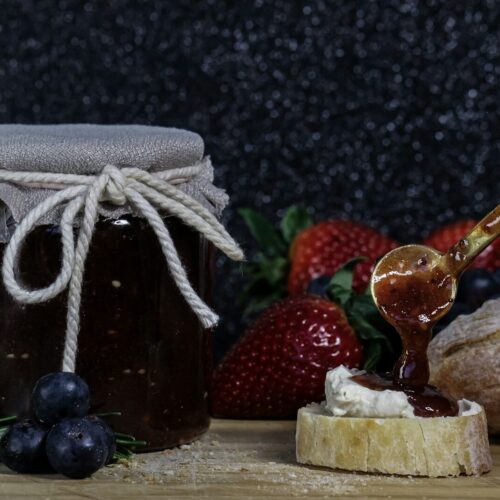 making jam a glass jar with a straw and a couple of strawberries
