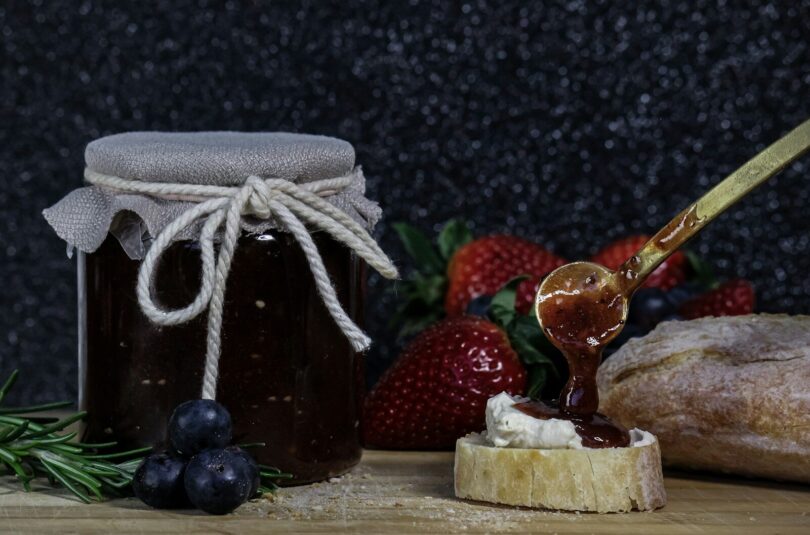 making jam a glass jar with a straw and a couple of strawberries