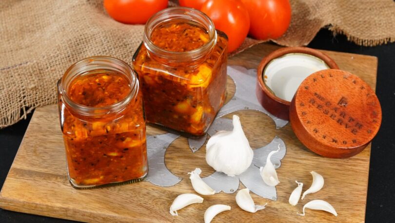 ix6g3cmgjli a wooden cutting board topped with jars of food