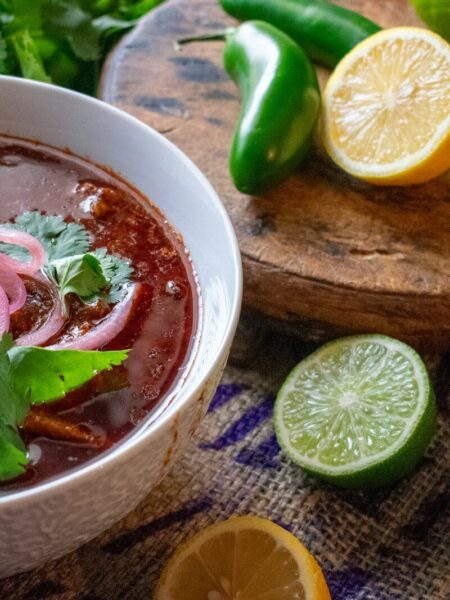 a bowl of chili soup with limes and cilantro